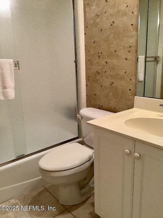 full bathroom with combined bath / shower with glass door, vanity, toilet, and tile patterned floors