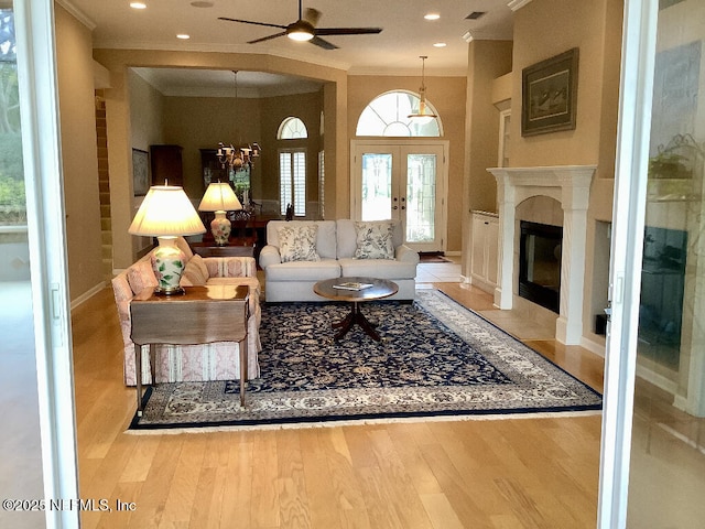 living area with french doors, visible vents, ornamental molding, a fireplace with flush hearth, and wood finished floors