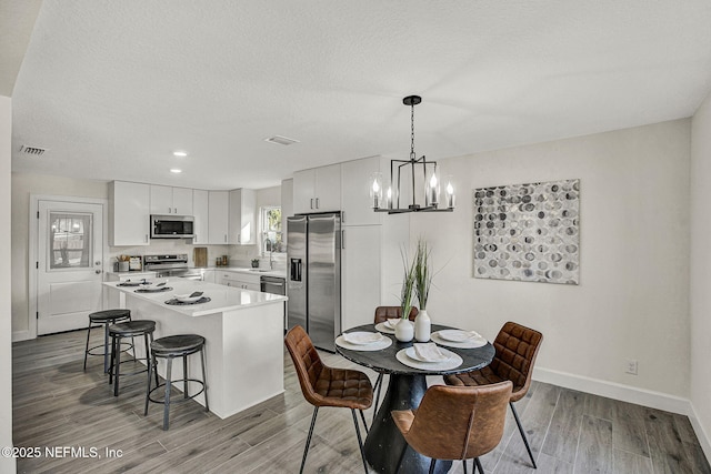 dining area featuring sink, an inviting chandelier, a textured ceiling, and light wood-type flooring