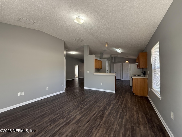 unfurnished living room featuring lofted ceiling, dark hardwood / wood-style flooring, and a textured ceiling