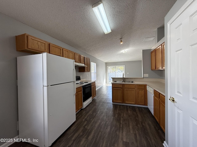 kitchen with sink, a textured ceiling, dark hardwood / wood-style floors, kitchen peninsula, and white appliances