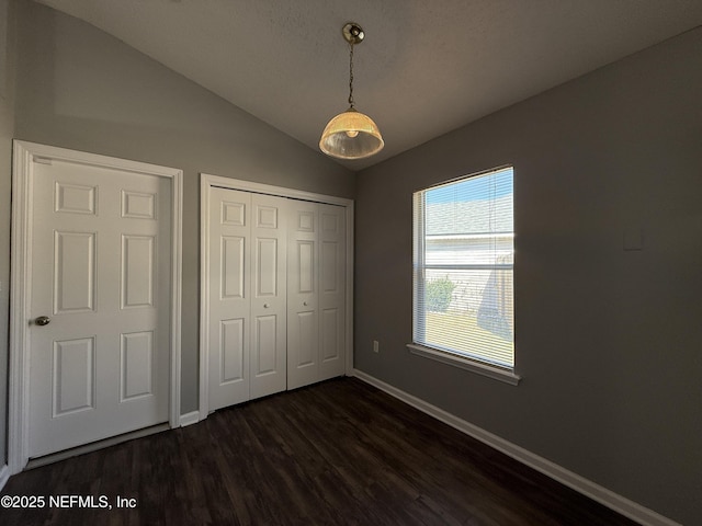 unfurnished bedroom with dark wood-type flooring, vaulted ceiling, and a closet