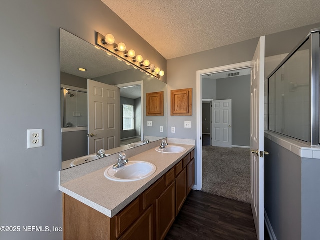 bathroom featuring hardwood / wood-style flooring, vanity, a textured ceiling, and a shower with shower door