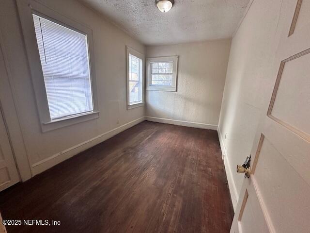 empty room featuring dark wood-type flooring and a textured ceiling