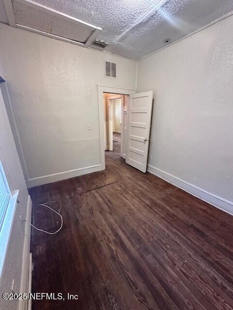 unfurnished room featuring dark wood-type flooring and a textured ceiling