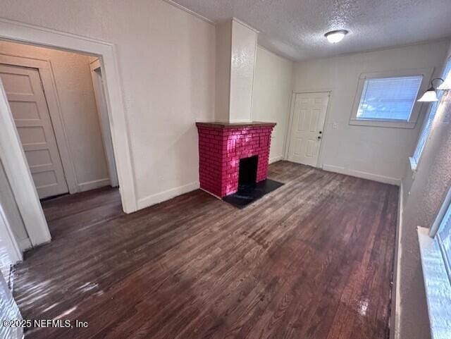 unfurnished living room with dark hardwood / wood-style flooring, a fireplace, and a textured ceiling