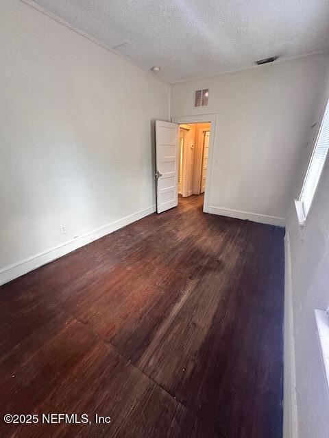 unfurnished room featuring dark wood-type flooring and a textured ceiling