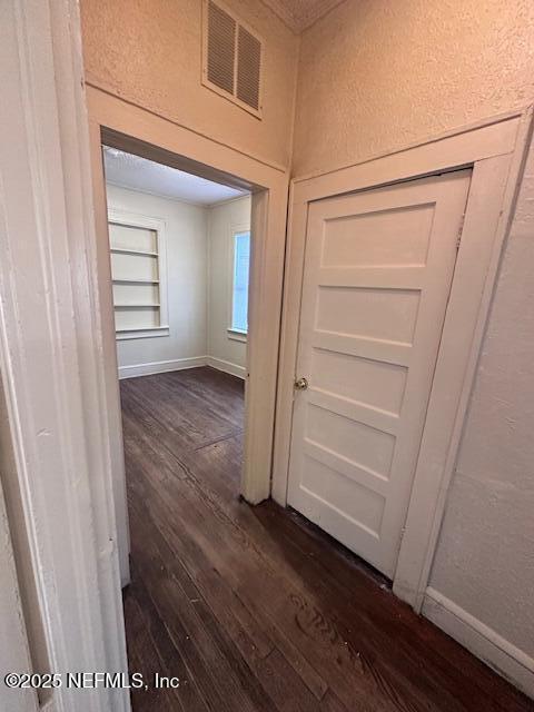 corridor featuring dark wood-type flooring and built in features