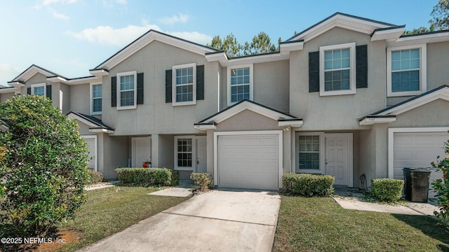 townhome / multi-family property featuring a garage, concrete driveway, a front lawn, and stucco siding