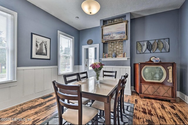 dining space featuring a textured ceiling, hardwood / wood-style floors, and plenty of natural light