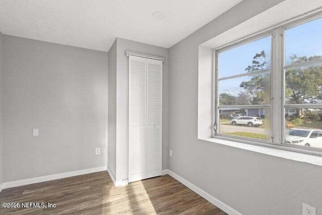 unfurnished bedroom featuring dark hardwood / wood-style floors and a closet