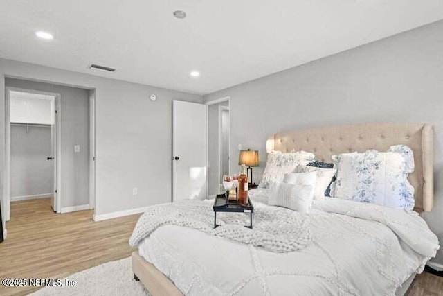 bedroom with hardwood / wood-style floors and a spacious closet