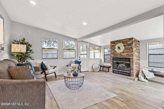 living room featuring lofted ceiling with beams, hardwood / wood-style flooring, and a fireplace