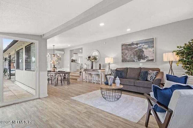 living room with beamed ceiling, wood-type flooring, and a chandelier