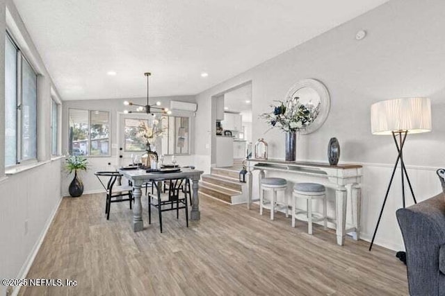 dining space with vaulted ceiling, an inviting chandelier, a textured ceiling, and light hardwood / wood-style floors