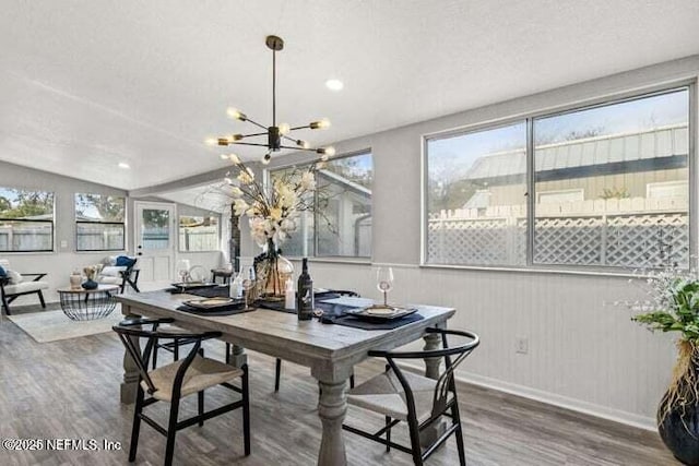 dining area featuring hardwood / wood-style flooring, lofted ceiling, a notable chandelier, and a textured ceiling