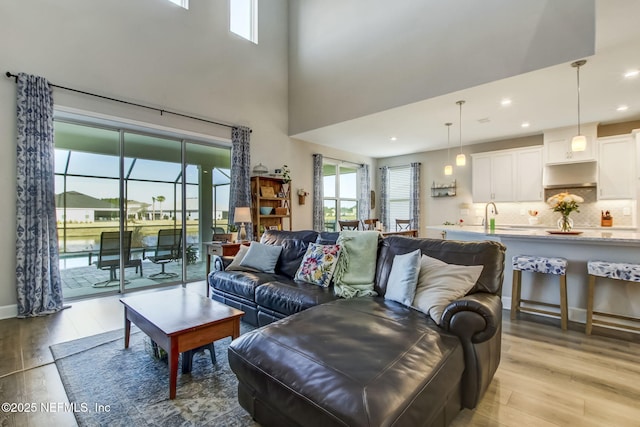 living room with sink, light hardwood / wood-style floors, and a high ceiling