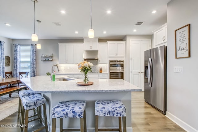 85248 Berryessa Way, Fernandina Beach, FL 32034 - kitchen with sink, hanging light fixtures, appliances with stainless steel finishes, a kitchen island with sink, and white cabinets
