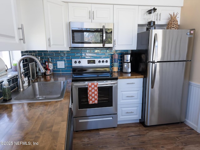 kitchen with tasteful backsplash, white cabinetry, sink, stainless steel appliances, and dark wood-type flooring