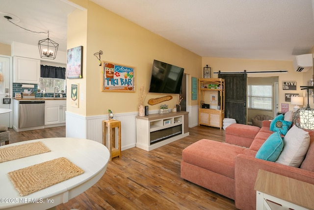 living room featuring hardwood / wood-style floors, a wall mounted air conditioner, sink, a chandelier, and a barn door