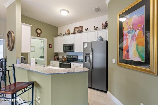 kitchen featuring a breakfast bar, appliances with stainless steel finishes, washing machine and dryer, white cabinets, and kitchen peninsula