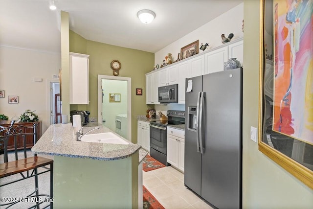 kitchen with a breakfast bar, sink, white cabinetry, light stone countertops, and black appliances