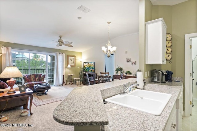 kitchen with sink, ceiling fan with notable chandelier, hanging light fixtures, and white cabinets