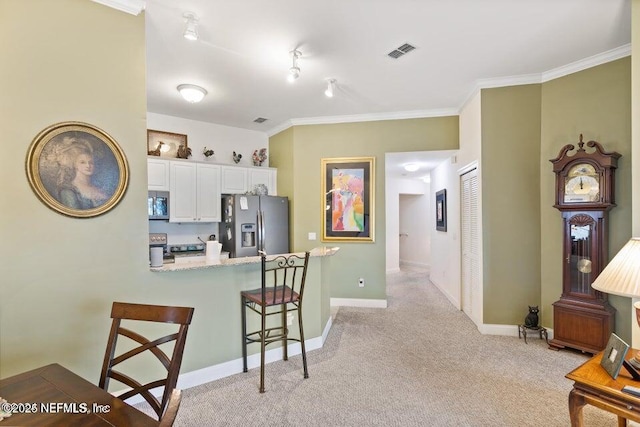 kitchen featuring light carpet, a kitchen breakfast bar, kitchen peninsula, stainless steel appliances, and white cabinets