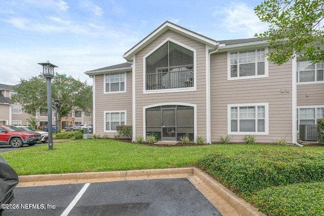 rear view of house with a balcony, cooling unit, and a lawn