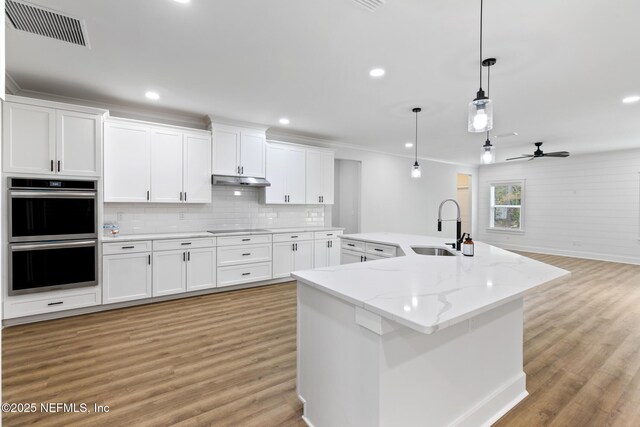 85034 Southern Creek Blvd, Fernandina Beach, FL 32034 - kitchen with double oven, decorative light fixtures, an island with sink, sink, and white cabinets