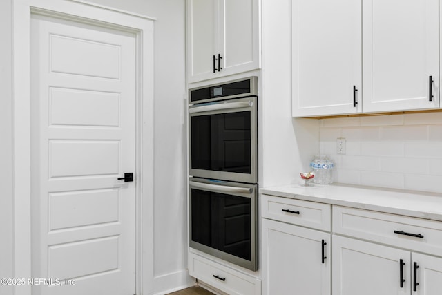 85034 Southern Creek Blvd, Fernandina Beach, FL 32034 - kitchen with white cabinetry, double oven, decorative backsplash, and light stone countertops