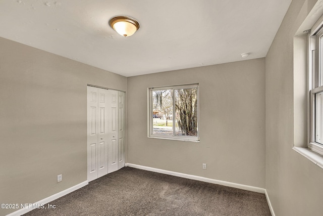 unfurnished bedroom with dark carpet and a closet