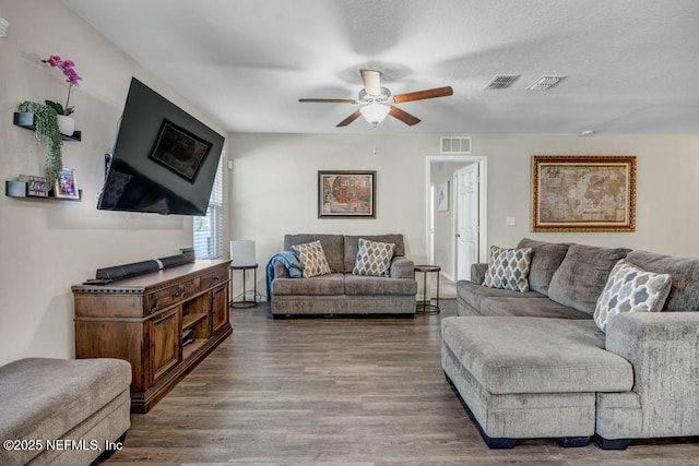 living area with wood finished floors, visible vents, and a ceiling fan