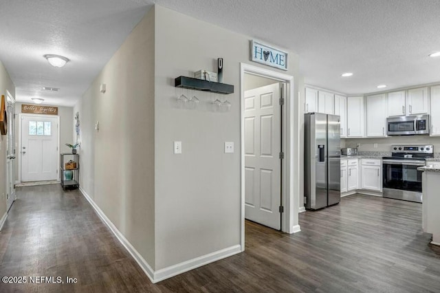 kitchen featuring baseboards, white cabinets, dark wood finished floors, stainless steel appliances, and a textured ceiling