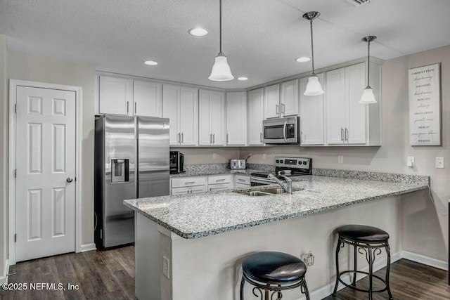 kitchen with appliances with stainless steel finishes, a breakfast bar, decorative light fixtures, and white cabinetry