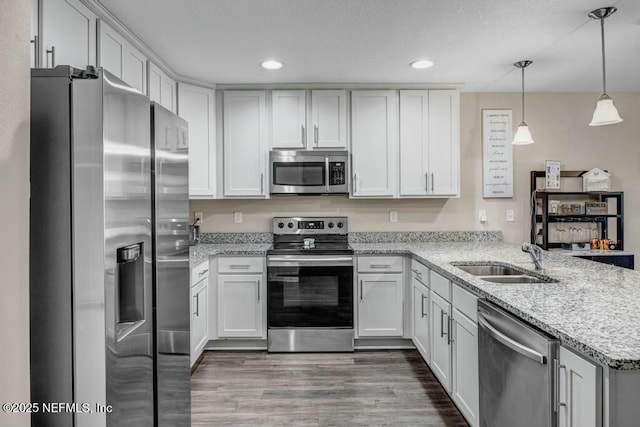 kitchen with stainless steel appliances, hanging light fixtures, a peninsula, and white cabinetry