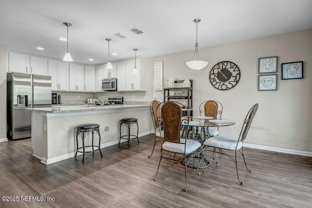 dining area with baseboards, visible vents, and wood finished floors