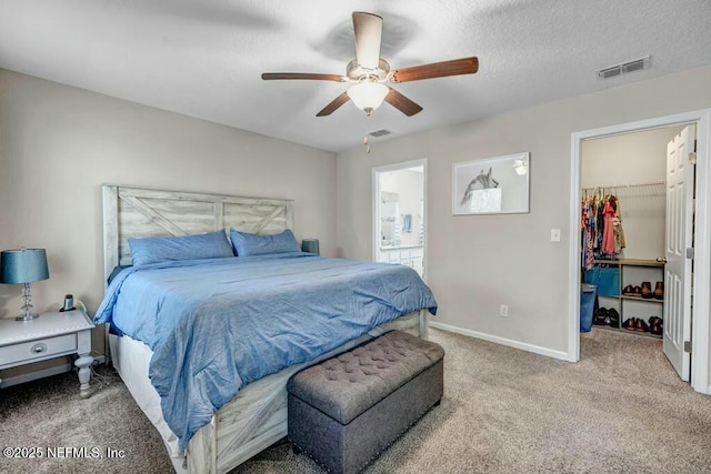 carpeted bedroom with a spacious closet, connected bathroom, visible vents, and baseboards