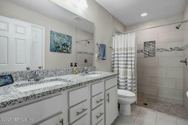 bathroom with double vanity, a tile shower, and a sink