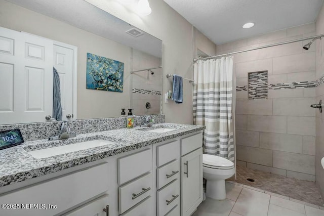 full bath with double vanity, tiled shower, and a sink