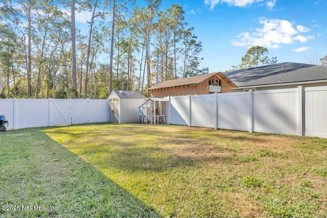 view of yard featuring an outbuilding, a gate, a fenced backyard, and a storage shed