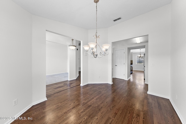 unfurnished dining area with dark wood-type flooring, a chandelier, and vaulted ceiling