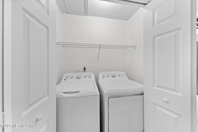 laundry area with a textured ceiling and washing machine and clothes dryer