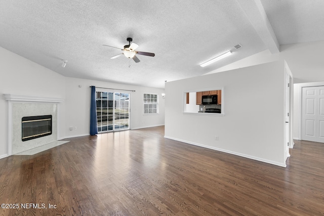 unfurnished living room with dark hardwood / wood-style floors, ceiling fan, a premium fireplace, and vaulted ceiling with beams