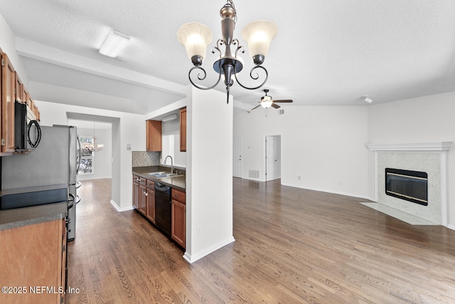 kitchen featuring sink, dark wood-type flooring, a fireplace, black appliances, and decorative backsplash