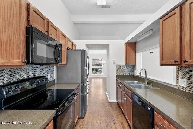 kitchen with sink, a textured ceiling, light wood-type flooring, decorative backsplash, and black appliances