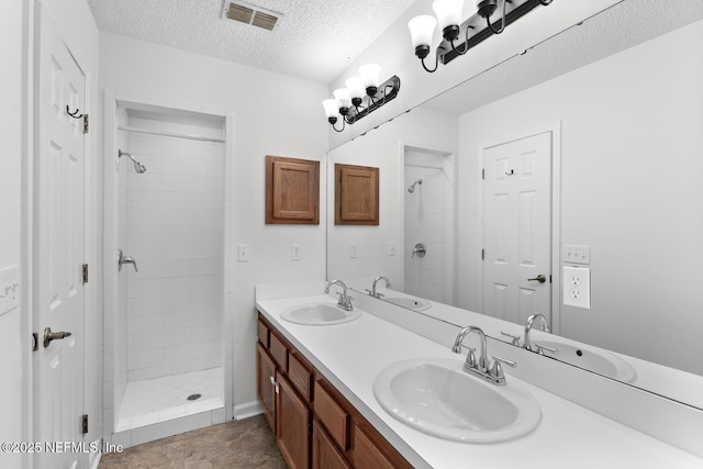 bathroom featuring vanity, a textured ceiling, and a tile shower