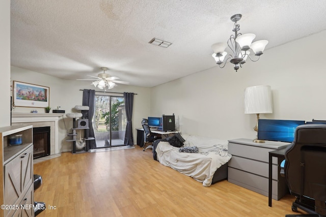 office space with hardwood / wood-style flooring, a tiled fireplace, ceiling fan with notable chandelier, and a textured ceiling