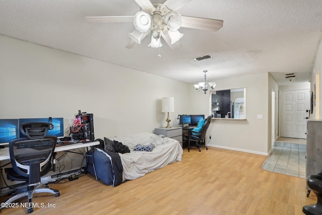 bedroom with hardwood / wood-style flooring, ceiling fan with notable chandelier, and a textured ceiling