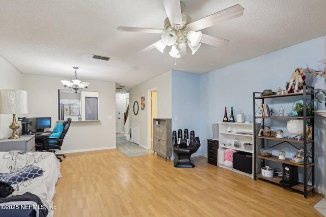 office area with ceiling fan with notable chandelier, a textured ceiling, and light wood-type flooring